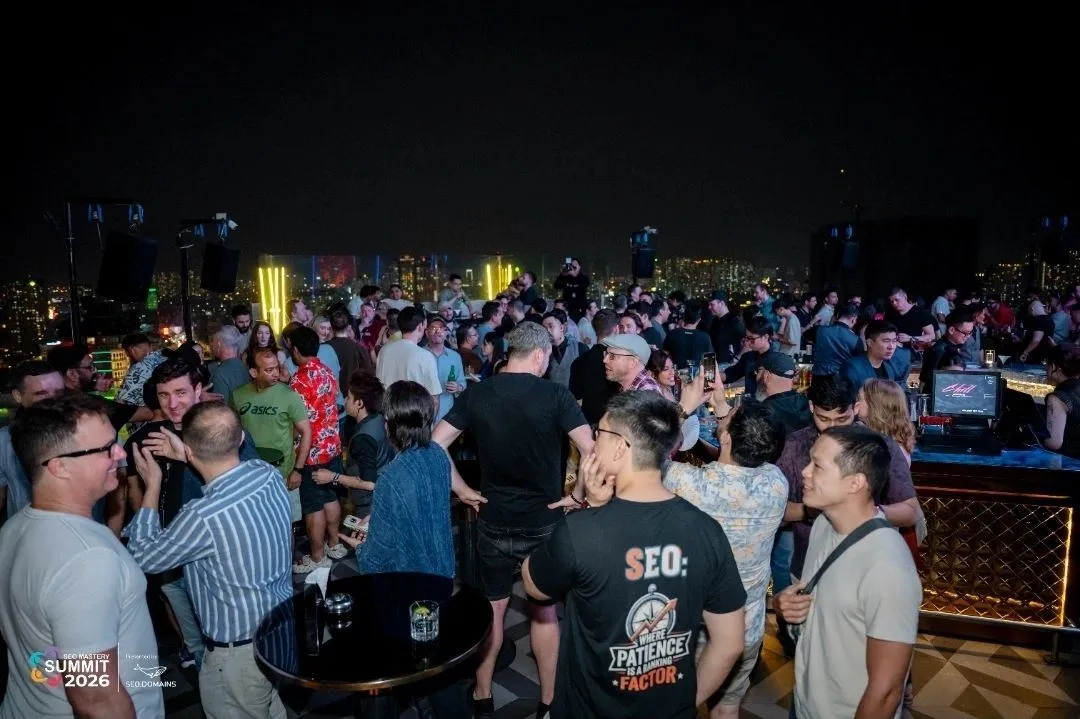 A crowded rooftop afterparty at SEO Mastery Summit 2026, with event branding and an SEO.Domains sponsor logo visible